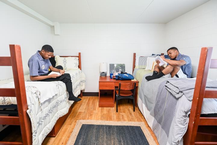 two male students on the beds in residence hall bedroom